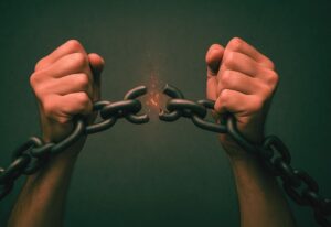 Mãos quebrando correntes mentais com poder dos versículos bíblicos de 2 Coríntios 10:5 para libertação espiritual